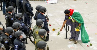 A supporter of a pro-Palestinian encampment places flowers at the feet of police at the University of California, Irvine, U.S., May 15, 2024. (AP Photo)