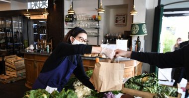 A customer buys food for take away at the L'Oseille restaurant where people can also buy fresh fruits and vegetables, Paris, France, May 15, 2020. (AFP Photo)