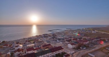 A sunset view over the Caspian Sea with Aktau's cityscape stretching along the shoreline, Kazakhstan. (Shutterstock Photo)
