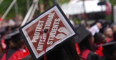 A Harvard University graduate wears a cap written "Protect International Students" as she protests Donald Trump's move to ban international students, Cambridge, U.S., May 28, 2025. (AA Photo)